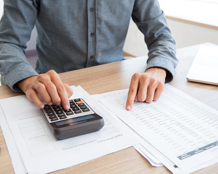 Close-up of unrecognizable man working with financial data. He using calculator and examining document. Financial inspector holding examination. Paperwork or finance concept